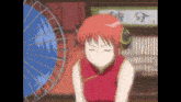 a girl in a red dress is sitting in front of a fan and umbrella .