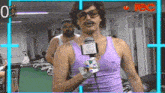 a man in a purple tank top is talking into a microphone