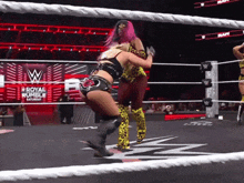two women in a wrestling ring with the words royal rumble saturday on the wall