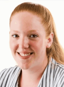 a woman with red hair is wearing a striped shirt and smiling for the camera