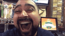 a man with a beard is laughing in front of a beer tap that says lager