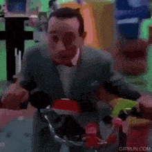 a man in a suit and bow tie is riding a red bicycle .