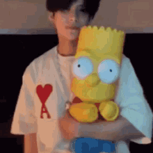 a man is holding a stuffed bart simpson toy in his arms .