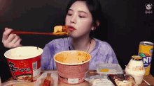 a woman is sitting at a table eating noodles with a spoon .