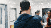 a man in a blue hoodie is standing in a hospital hallway with a group of people .