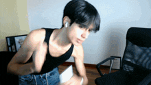 a man in a black tank top is standing in front of a black chair
