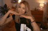 a woman making a funny face with her hands while wearing a black shirt that says ' aa ' on it