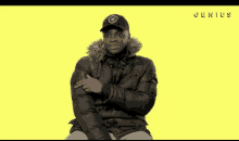 a man wearing a black jacket and a black hat with the word genius on it