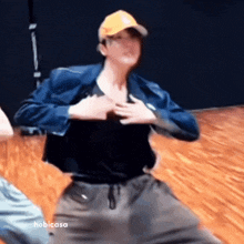 a man wearing a baseball cap and a blue jacket is dancing on a wooden floor .
