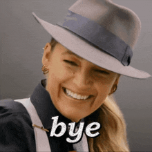 a woman wearing a fedora hat is smiling and the word bye is on the bottom