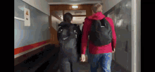 a man in a red jacket is walking down a hallway