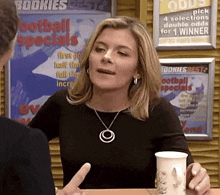 a woman is talking to a man in front of a sign that says bookies