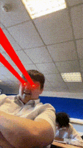 a man with red lasers coming out of his eyes sitting in a classroom