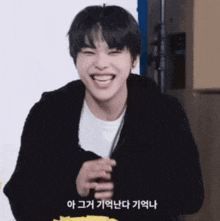 a young man wearing a black jacket and a white shirt is laughing