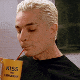 a man is drinking from a yellow cup that says kiss the librarian