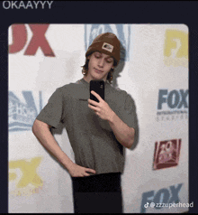 a young man taking a selfie in front of a fox sign