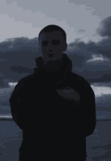 a man in a black jacket is standing in front of a stormy sky