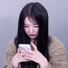 a woman with long black hair is looking at a cell phone