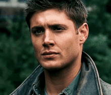 a close up of a man 's face with a leather jacket on