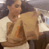 a woman is holding a bag of food in her arms .