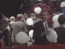 a man holding a white balloon in front of a crowd with a sign that says ew on it