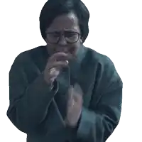 a woman wearing glasses and a sweater is clapping