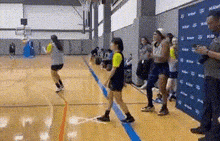 a group of people are standing on a basketball court in a gym .