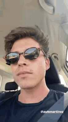 a man wearing sunglasses is sitting in a car with the name @aulemartinez on the bottom right