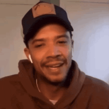 a man wearing a hat and ear buds is smiling .