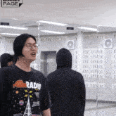 a man wearing a black shirt that says alien radio stands in front of a mirror