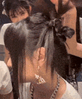 a woman wearing a necklace and earrings has her hair in a bun .