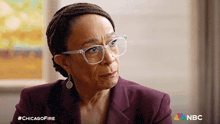 a woman wearing glasses and a purple jacket with a nbc logo