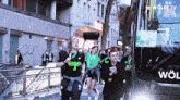 a group of people are walking in front of a bus that says wolfe tv