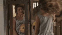 a woman is standing in front of a mirror and looking at herself .