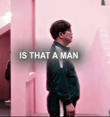 a man is standing in front of a pink wall with the words is that a man written on it