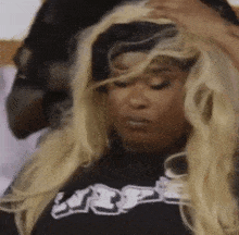 a woman wearing a wig and a black shirt is sitting in a chair .