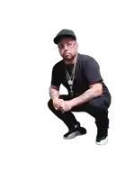 a man with a tattoo on his arm kneeling down with his hands folded