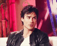 a man in a black leather jacket is sitting on a white couch