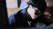 a young man wearing sunglasses and a bow tie is sitting in front of a computer .