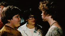 a group of young people are standing next to each other and looking at each other in a dark room .