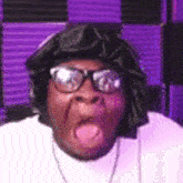 a man wearing glasses and a black hat is sticking out his tongue .