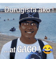 a man wearing a hat and a t-shirt is laughing on a beach ..