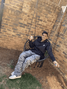 a man in a black hoodie is sitting on a swing