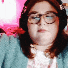 a woman wearing glasses and headphones looks down with her eyes closed
