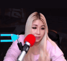 a woman in a pink shirt is sitting in front of a red microphone