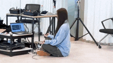 a woman is sitting on the floor in front of a laptop computer ..