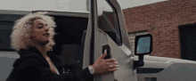 a woman is getting out of a white truck .