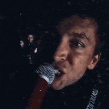 a man singing into a microphone with a red cup in front of his face