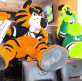 a tiger and a lizard mascot are sitting in a chair