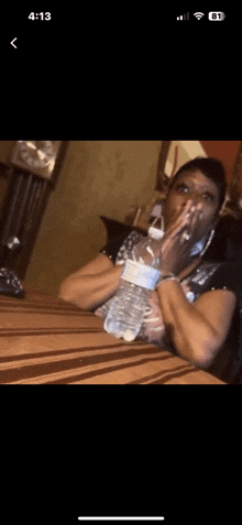 a woman sitting at a table with a bottle of water